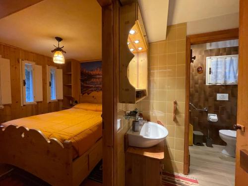 uma casa de banho com uma cama e um lavatório num quarto em I Larici - Appartamento per sognare em Alpe Devero