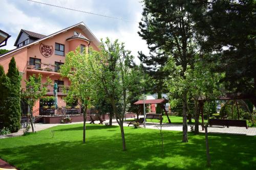 a building with a green yard with trees in front of it at Pensiunea Roua Muntilor in Vadu Crişului