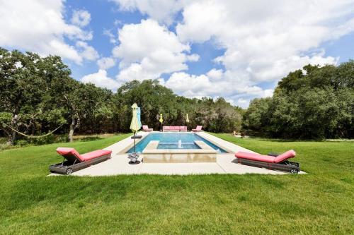 a pool with two chairs and an umbrella in the grass at Get Back to Nature at Secluded Hill Country Oasis in Driftwood