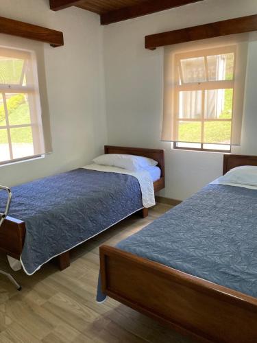 a bedroom with two beds and two windows at Los Héroes in Nuevo Arenal
