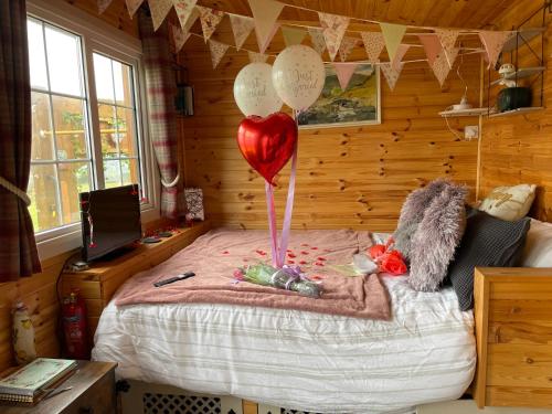 a bedroom with a bed with a heart balloon at Keepers Shepherd hut with Hot Tub in Whitby