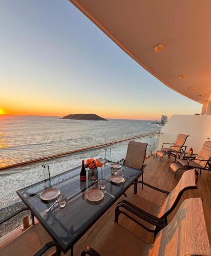 a table on a balcony with a view of the ocean at Departamento a pie de playa en Camino al Mar in Mazatlán