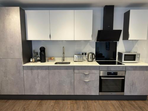 a kitchen with white cabinets and stainless steel appliances at York Minster Apartment in York