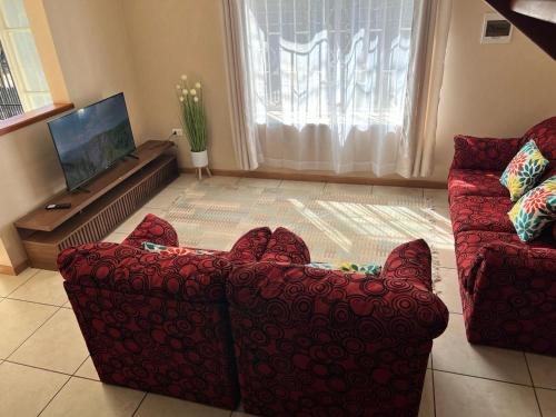 sala de estar con sofá rojo y TV en Amplia Casa 8 dormitorios 4 baños Avenida Lircay, en Talca
