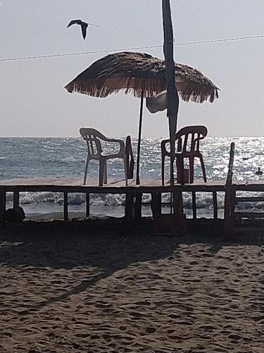 a table with chairs and an umbrella on the beach at Canadian House Rincón del Mar in Rincón