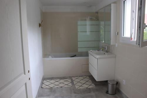 un bagno bianco con vasca e lavandino di Maison en Normandie a Londinières