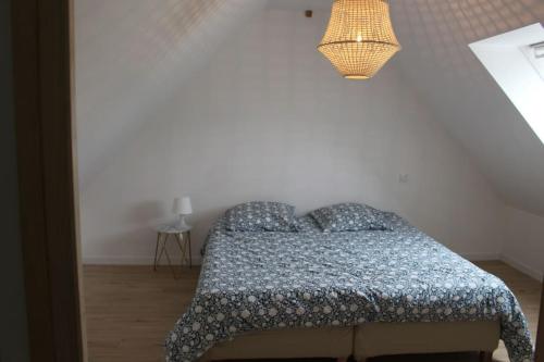 una camera da letto con un letto con un piumone blu e una lampada di Maison en Normandie a Londinières