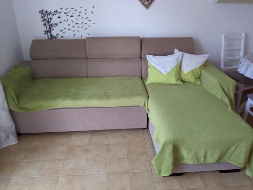 a bed with a green blanket and pillows on it at Emilija Apartments Privlaka in Privlaka