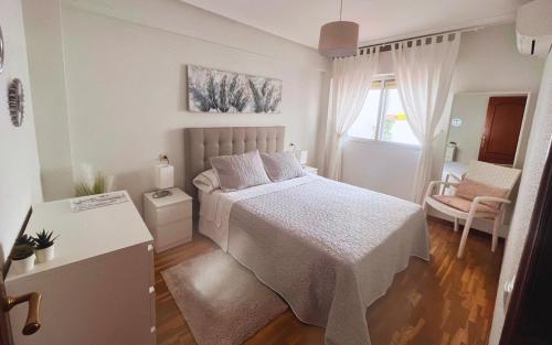 ein weißes Schlafzimmer mit einem Bett und einem Stuhl in der Unterkunft Apartamento La Plaza en Toro Zamora in Toro
