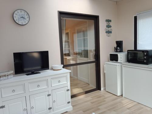 - un salon avec une télévision sur une commode blanche dans l'établissement Le Funiculaire, au Tréport