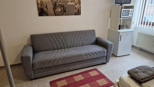 - un canapé gris dans le salon doté d'un réfrigérateur dans l'établissement Gästezimmer 2, à Mönchengladbach
