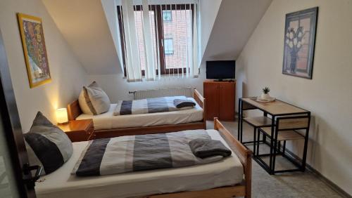 Cette petite chambre comprend deux lits et une télévision. dans l'établissement Gästezimmer 2, à Mönchengladbach