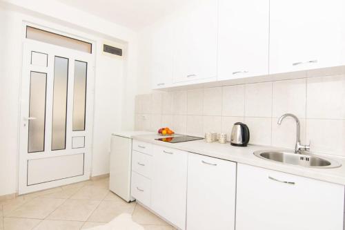 a white kitchen with white cabinets and a sink at Apartments Savić in Herceg-Novi