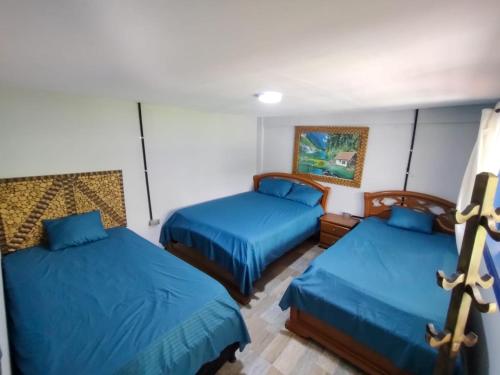2 Betten in einem Zimmer mit blauer Bettwäsche in der Unterkunft Hacienda la riviera in Santa Rosa de Cabal