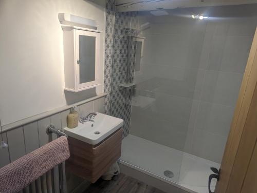 a white bathroom with a sink and a shower at Whitby Sea View Cottage in Whitby