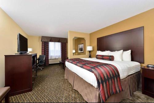 ein Hotelzimmer mit einem großen Bett und einem TV in der Unterkunft Baymont by Wyndham Ardmore I-35 in Ardmore