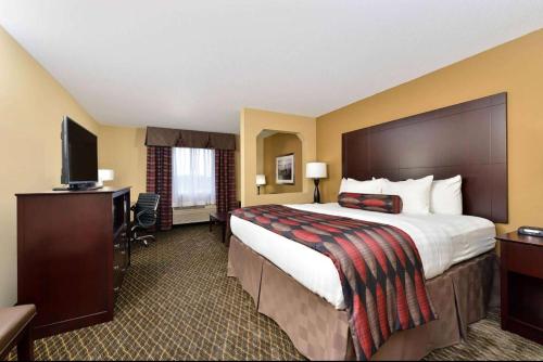 a hotel room with a large bed and a television at Baymont by Wyndham Ardmore I-35 in Ardmore