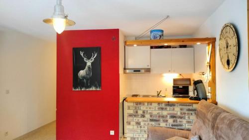 a kitchen with a red wall with a deer on it at Résidence La Grande Montagne - 2 Pièces pour 4 Personnes 151 in Modane
