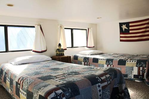 Dos camas en una habitación con una bandera americana en la pared en Oceanview Cabin 28 W Jacuzzi & Terrific Views, en Smith River