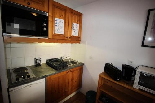 eine kleine Küche mit einer Spüle und einer Mikrowelle in der Unterkunft Chalets De La Vanoise - 2 Pièces pour 4 Personnes 171 in Villarodin-Bourget