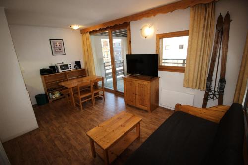 ein Wohnzimmer mit einem TV und einem Tisch in der Unterkunft Chalets De La Vanoise - 2 Pièces pour 4 Personnes 171 in Villarodin-Bourget