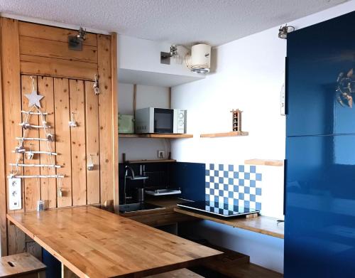 une cuisine avec une table en bois et un mur bleu dans l'établissement Résidence Cachette - Superbe 2 pièces cabine 4 personnes à Arc 1600, proche des pistes et proche des commerces MAE-7831, à Arc 1600