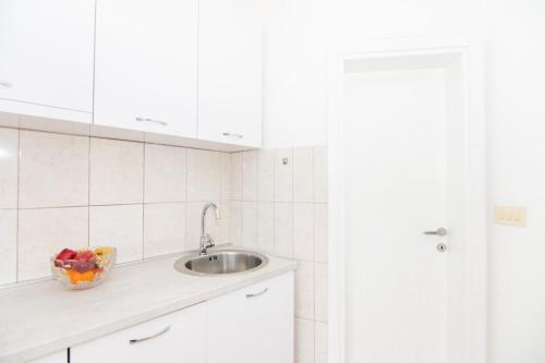 a kitchen with a sink and a bowl of fruit at Apartments Savić in Herceg-Novi
