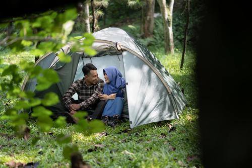 a man and woman sitting in a tent at Putu Ubud Glamping Camping in Bedahulu