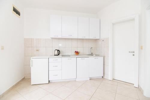 a white kitchen with white cabinets and a sink at Apartments Savić in Herceg-Novi