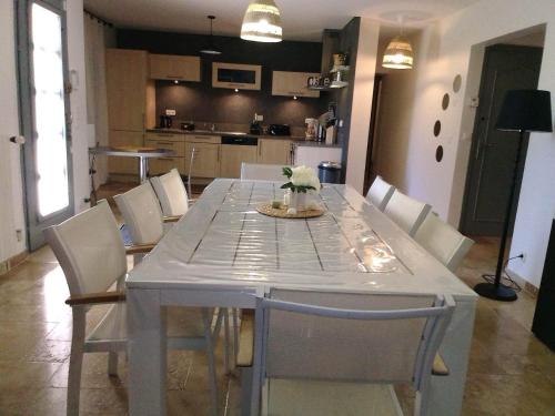 a dining room table with white chairs and a kitchen at GITE Thiron Gardais LA COUR aux PAUVRES in Thiron-Gardais