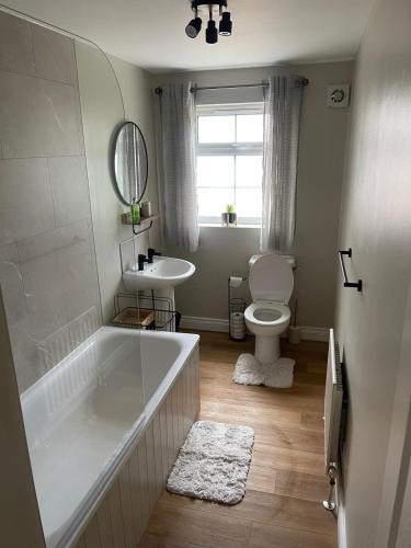 a bathroom with a tub and a toilet and a sink at Luxurious apartment Gilnahirk in Belfast