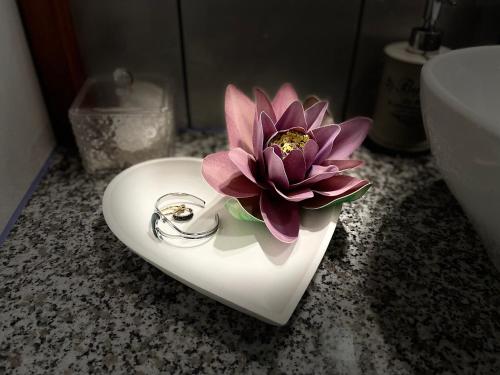 una flor rosa en un fregadero blanco con forma de corazón en Marta Guest House, en Gyenesdiás