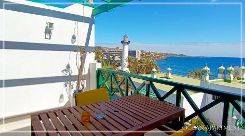 een balkon met een houten tafel en uitzicht op de oceaan bij Ocean Apartment Gran Canaria in Maspalomas
