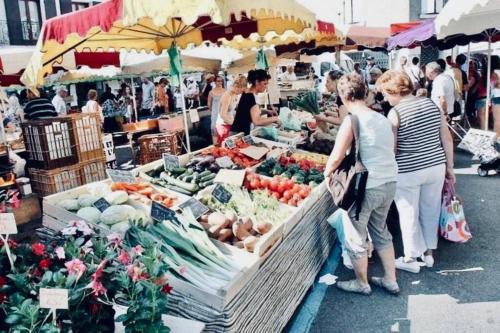 a group of people standing at a farmers market at Appartement Cosy centre-ville in Ribérac