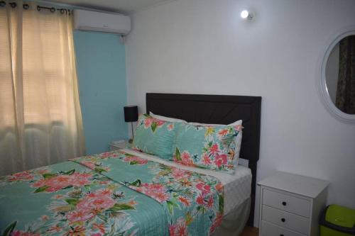 1 dormitorio con 1 cama con sábanas florales y ventana en Belle Zoon Villa en Cap Estate