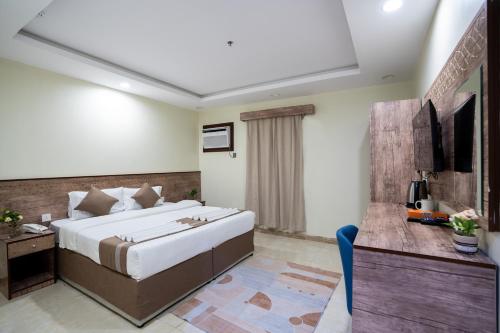 una camera d'albergo con un grande letto e una scrivania di فندق سما سول للشقق a La Mecca