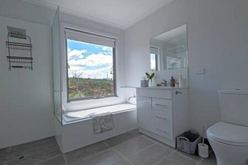 Baño blanco con ventana y aseo en Merino Cottage Meadowbank Lake, en Ellendale