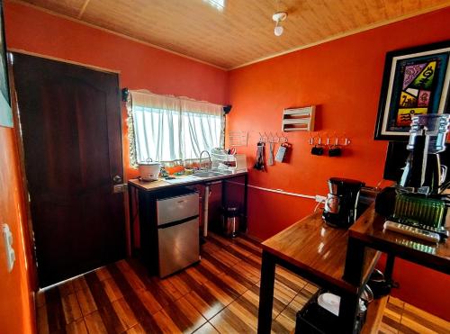 a kitchen with orange walls and a counter and a sink at Cabinas Río Frío in San Rafael