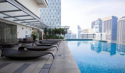 a hotel swimming pool with chairs and buildings at KLCC Cormar Premium Suites at Kuala Lumpur City Center in Kuala Lumpur