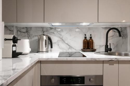 - une cuisine avec des murs en marbre blanc et un évier dans l'établissement Suite Cathédrale haut de gamme + Parking - N°8, à Rouen