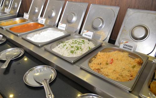 a buffet with trays of food and spoons at Hotel ABM International in Bengaluru