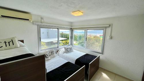 een slaapkamer met 2 bedden en een groot raam bij Casa Calma Puerto del Aguila in Potrero de Garay