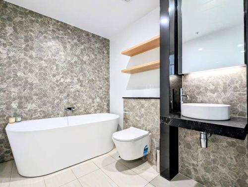 uma casa de banho com uma banheira, um WC e um lavatório. em 舒适的2卧公寓，带室内泳池和桑拿 em Sidney