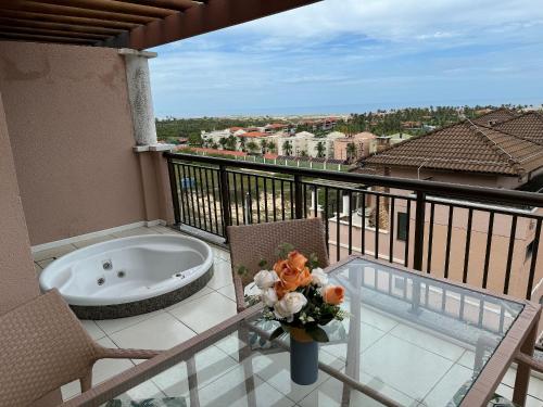 a balcony with a tub and a vase of flowers on a table at Apto. Beverlly Hills, Próx. Beach Park in Aquiraz
