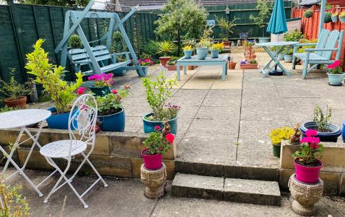 een patio met tafels en stoelen en potplanten bij Purple dream double bedroom in Cheltenham