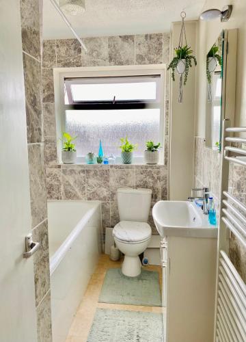 a bathroom with a toilet and a tub and a sink at Purple dream double bedroom in Cheltenham