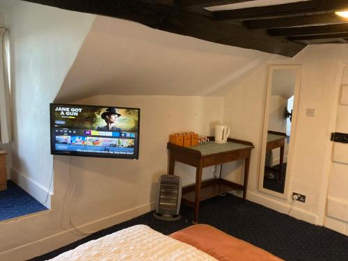 a room with a tv on a wall with a bed at Bryntirion Farmhouse Room with own bathroom in Llanfair Caereinion