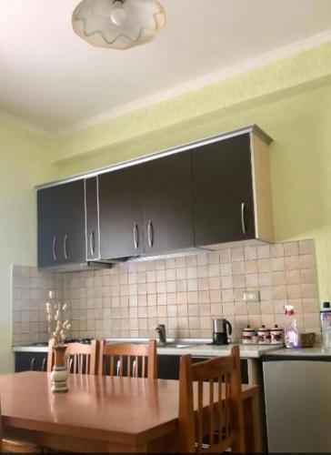 a kitchen with a wooden table and black cabinets at George’s Apartment in Orikum