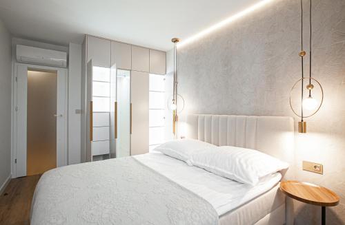 a bedroom with a white bed and two lights at KOBIELA APARTMENTS Dębowe Tarasy in Katowice