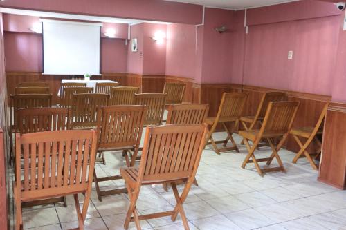 a room with a bunch of chairs and a screen at Hotel Garden Latorre in Iquique
